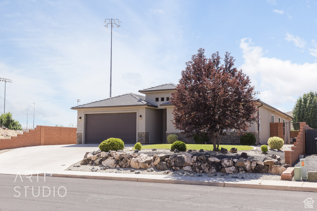 View of front of property with an attached garage, driveway, stucco siding, and stone siding