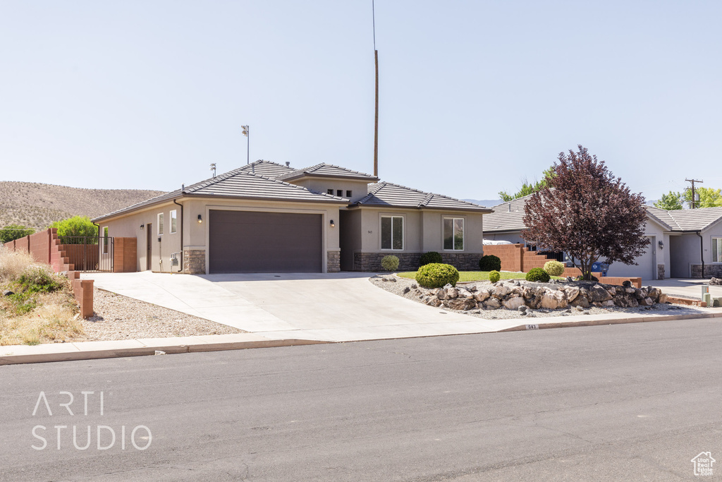 View of front of home with stone siding, a garage, stucco siding, driveway, and a tile roof