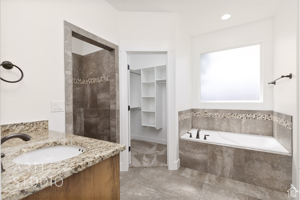 Bathroom featuring a garden tub, a walk in closet, vanity, and tiled shower