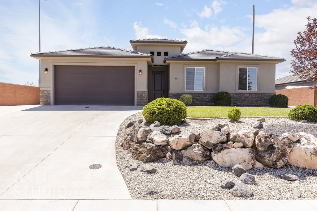 Prairie-style house featuring stone siding, driveway, an attached garage, stucco siding, and a tile roof