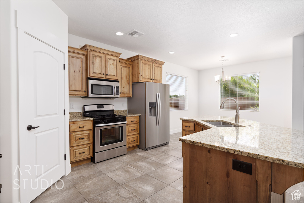Kitchen with stainless steel appliances, a chandelier, plenty of natural light, light stone counters, and recessed lighting