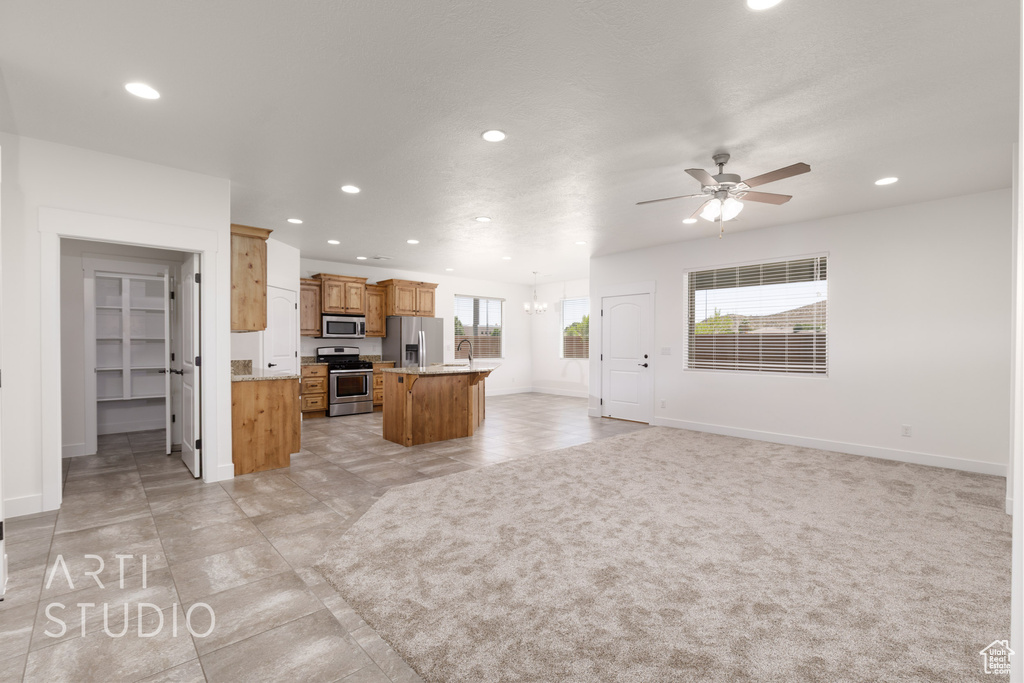 Kitchen featuring stainless steel appliances, recessed lighting, open floor plan, ceiling fan, and a kitchen island with sink