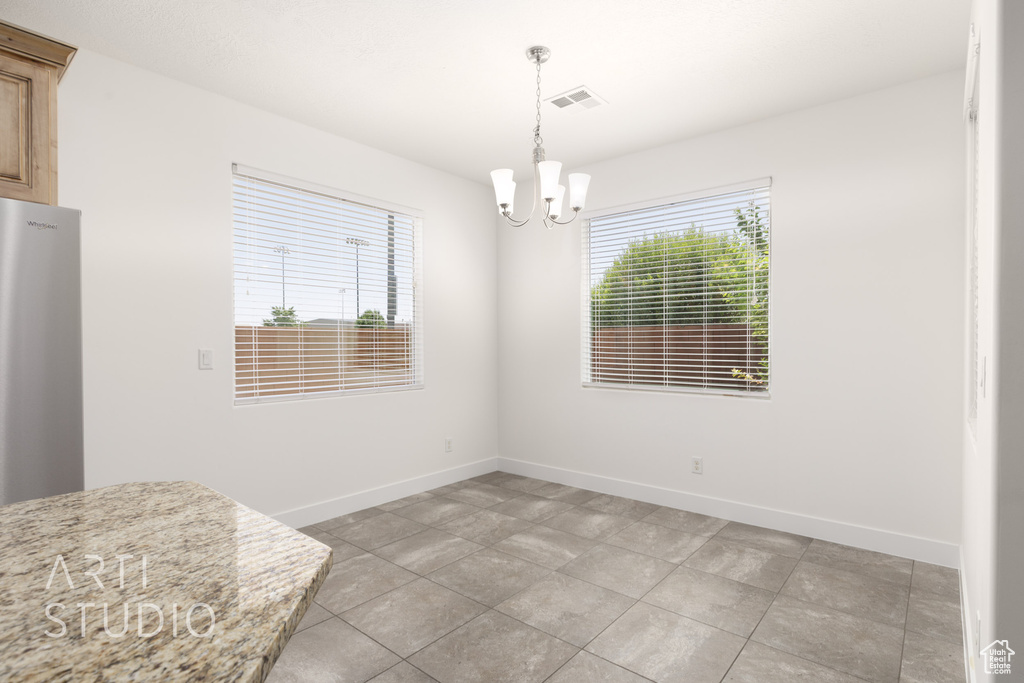 Unfurnished dining area with a chandelier and light tile patterned floors