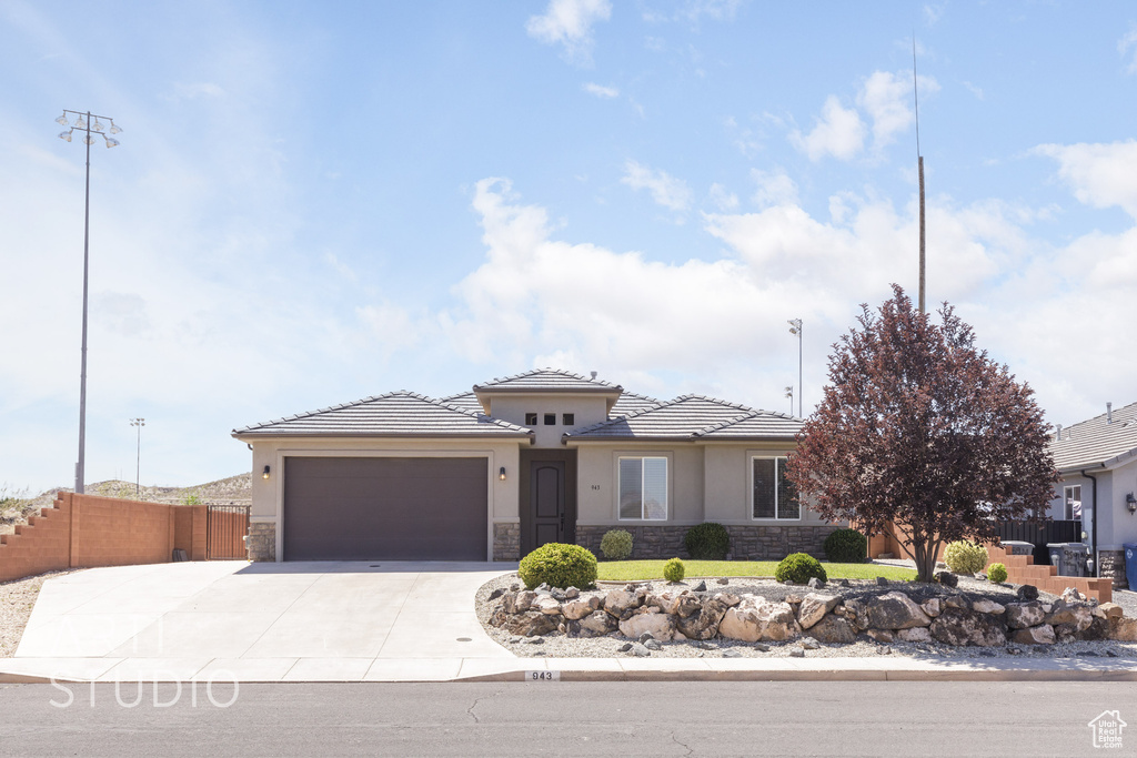 View of front of home with stone siding, stucco siding, an attached garage, driveway, and a tiled roof