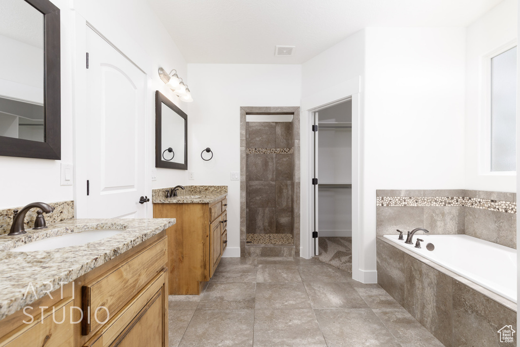 Bathroom with a stall shower, two vanities, a garden tub, and a walk in closet