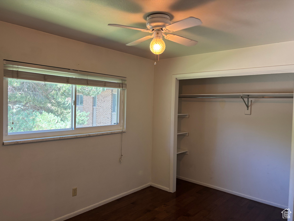 Unfurnished bedroom featuring dark wood-style floors, a closet, and ceiling fan