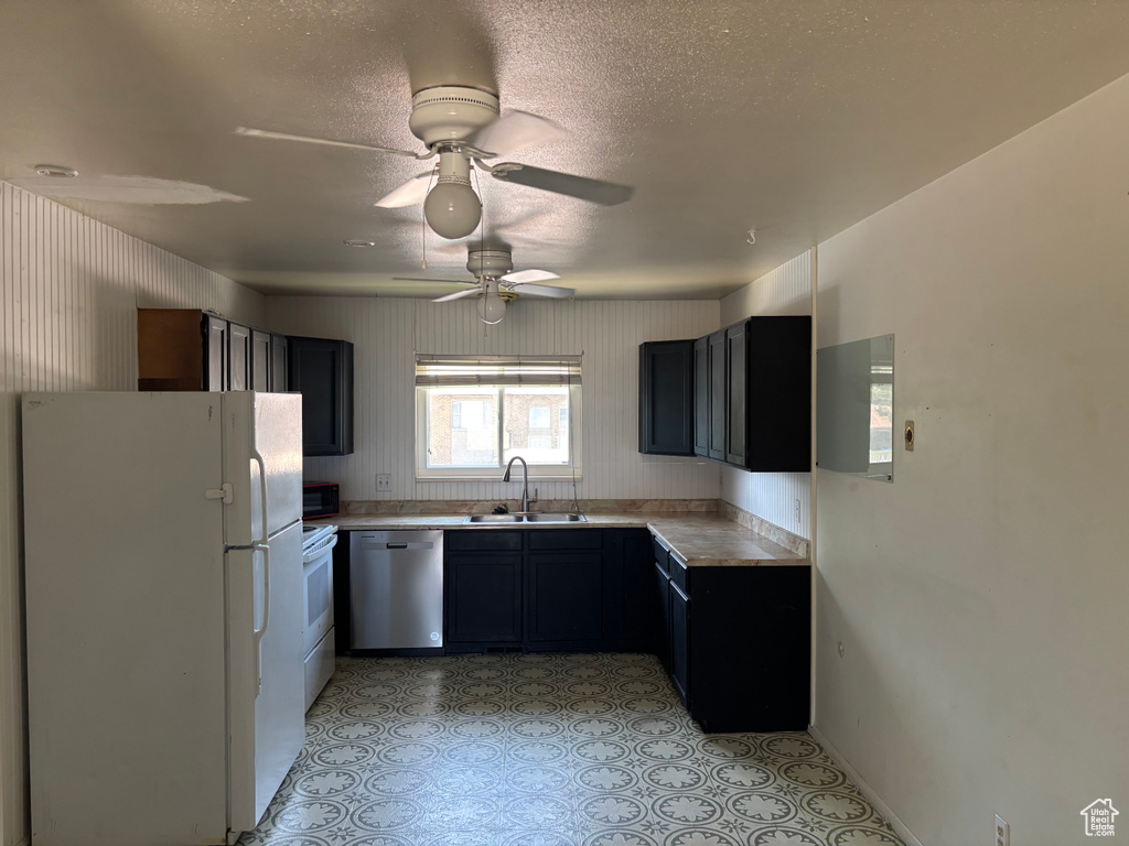 Kitchen with white appliances, light countertops, ceiling fan, and a textured ceiling