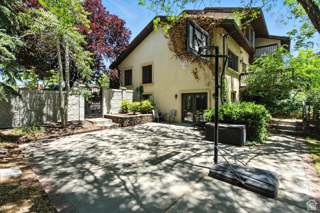 Back of property featuring stucco siding, french doors, a gate, a patio area, and a balcony