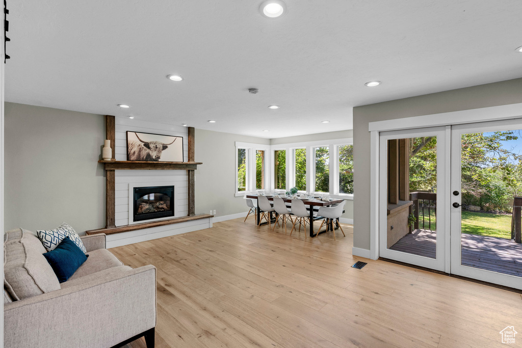 Living room with french doors, recessed lighting, a fireplace, and light wood-type flooring