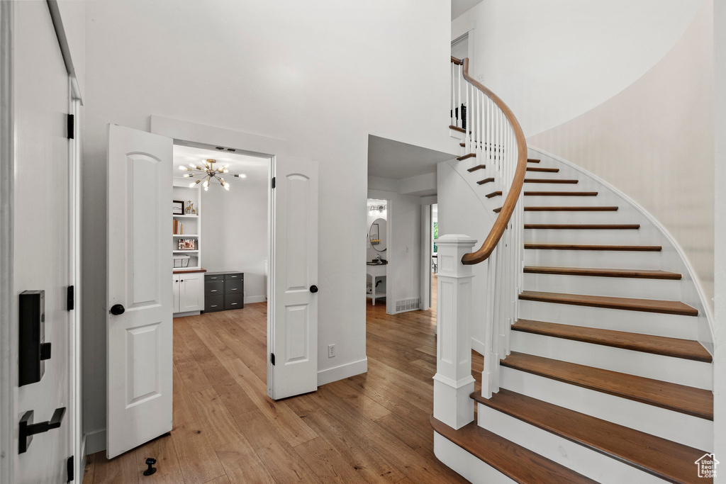 Staircase featuring wood finished floors, a towering ceiling, and a chandelier