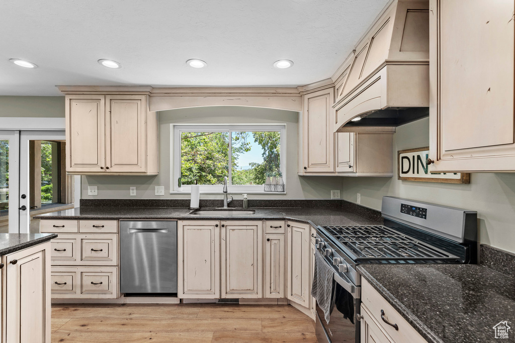 Kitchen featuring appliances with stainless steel finishes, light wood-style floors, recessed lighting, dark stone counters, and cream cabinets