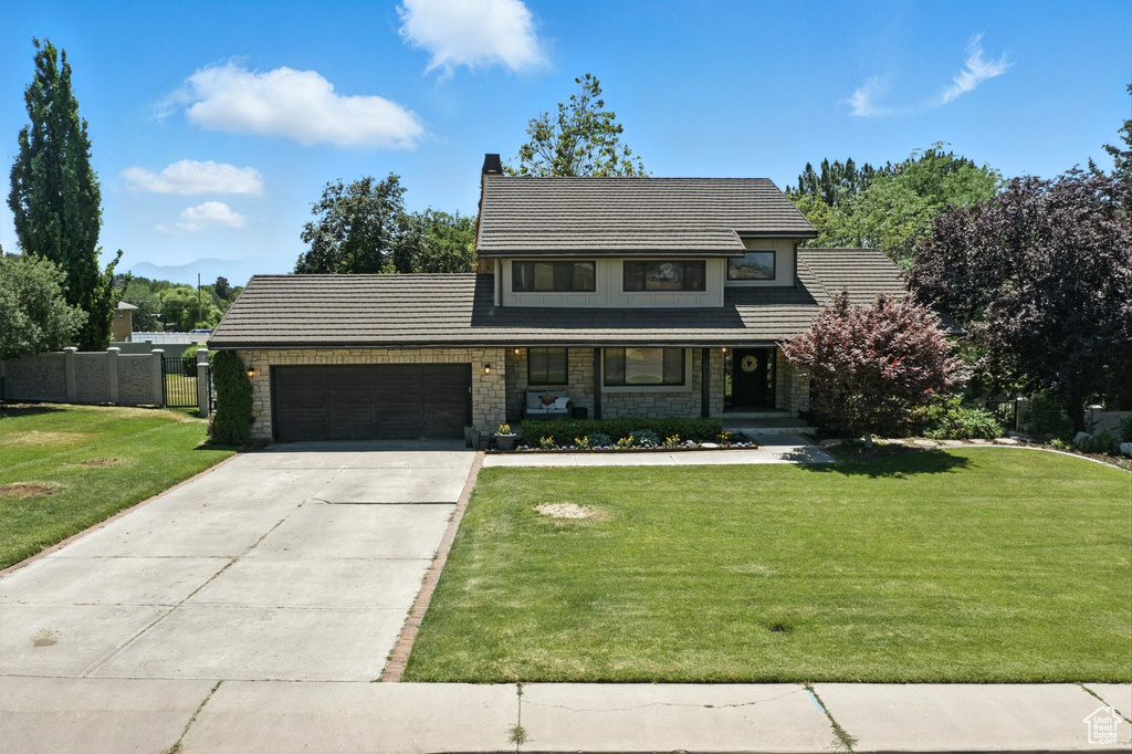 View of front facade featuring an attached garage, stone siding, driveway, and a chimney