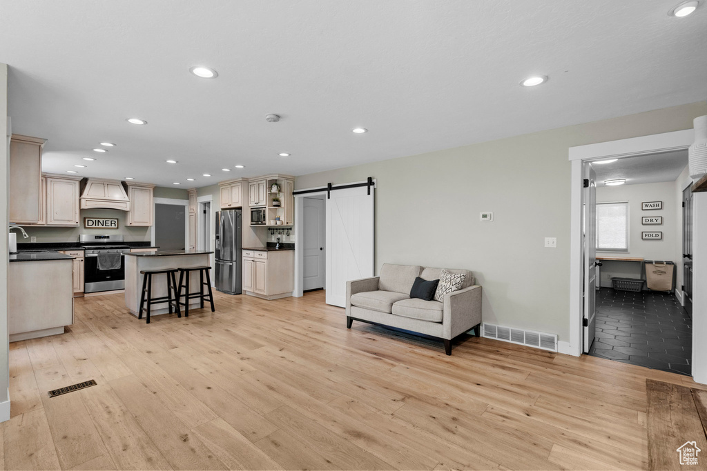 Living room featuring a barn door, light wood-style floors, and recessed lighting