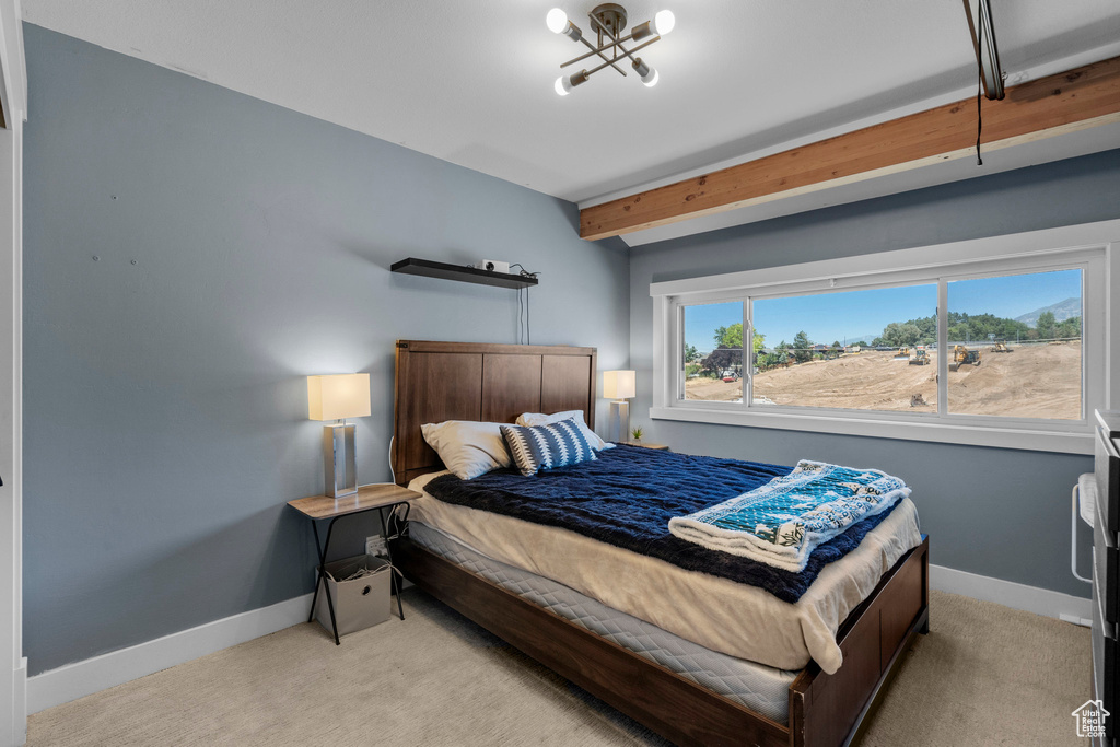Bedroom with light colored carpet and beam ceiling
