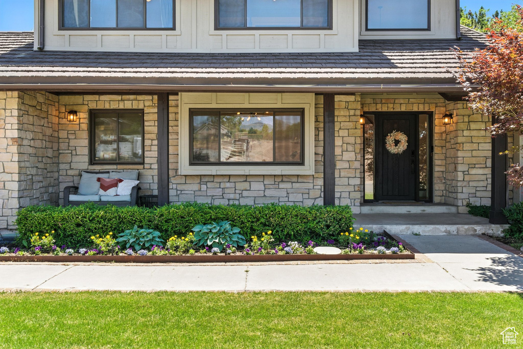 Doorway to property featuring covered porch and stone siding