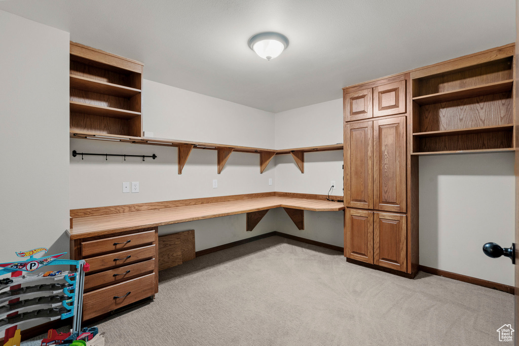Unfurnished office featuring built in desk and light colored carpet