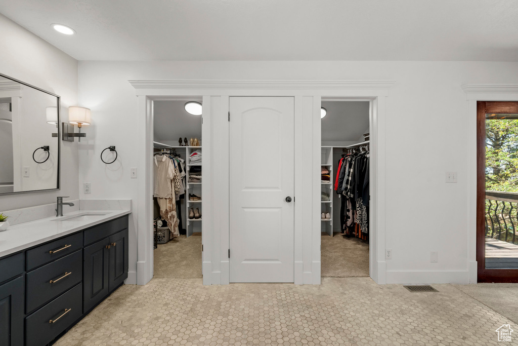 Full bath with vanity, a spacious closet, tile patterned floors, and recessed lighting