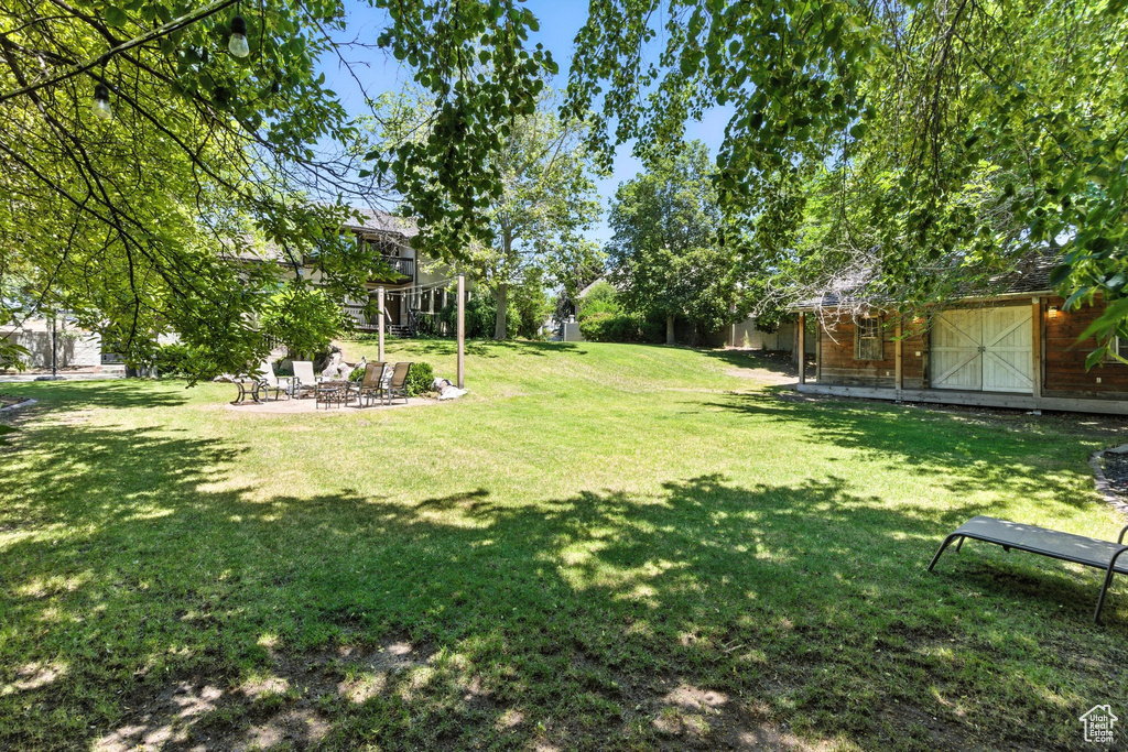 View of grassy yard with a fire pit, a storage shed, and a patio