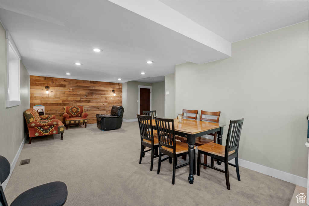 Dining room with wooden walls, recessed lighting, light colored carpet, and an accent wall
