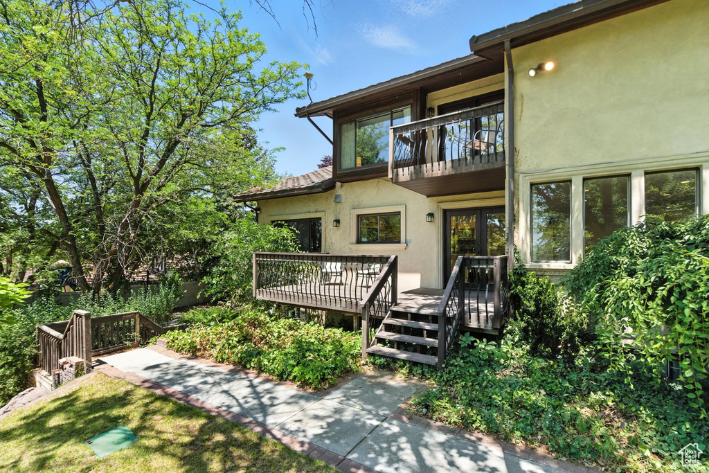 Doorway to property with a balcony, stucco siding, and a deck