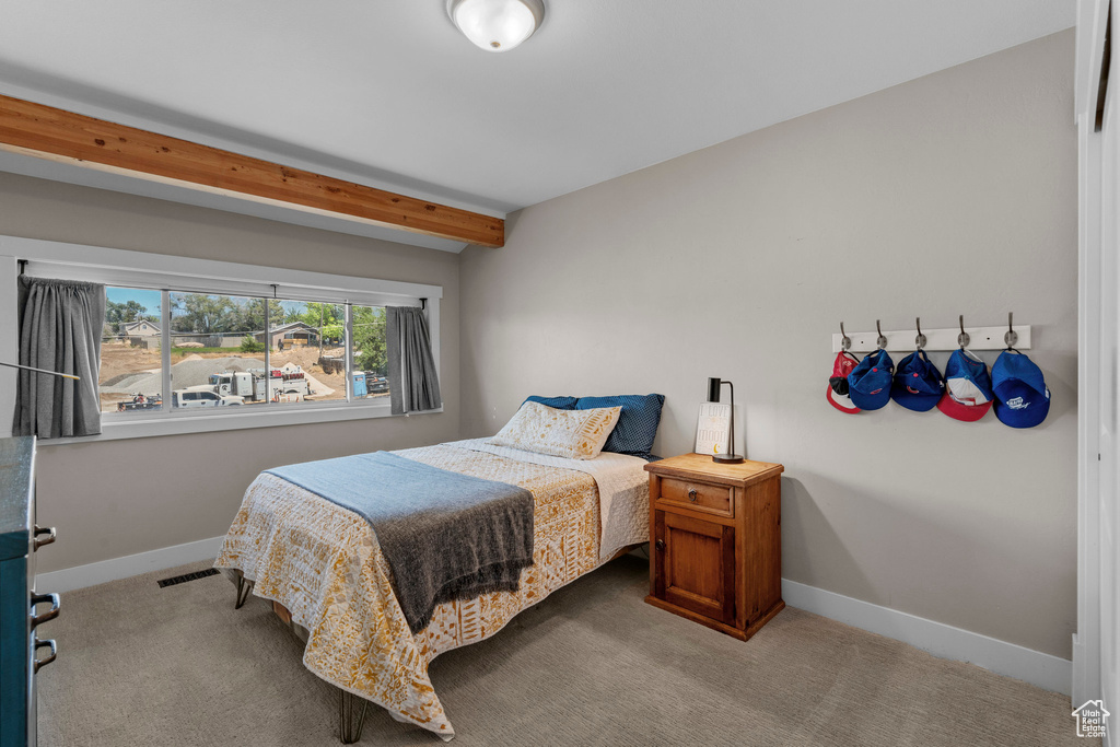 Carpeted bedroom featuring baseboards and beamed ceiling