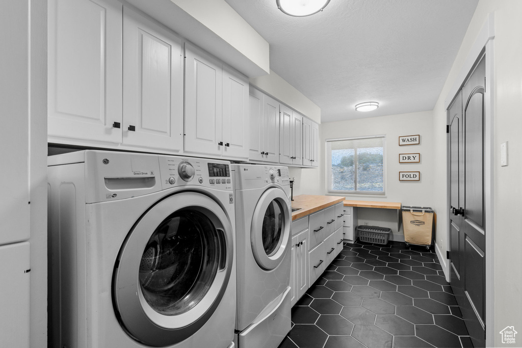 Washroom featuring cabinet space, washer and dryer, and dark tile patterned flooring
