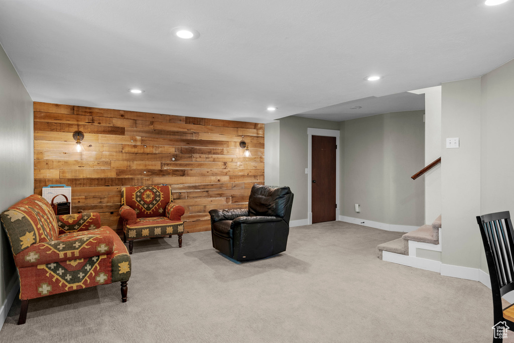 Carpeted living area featuring wood walls, stairs, and recessed lighting
