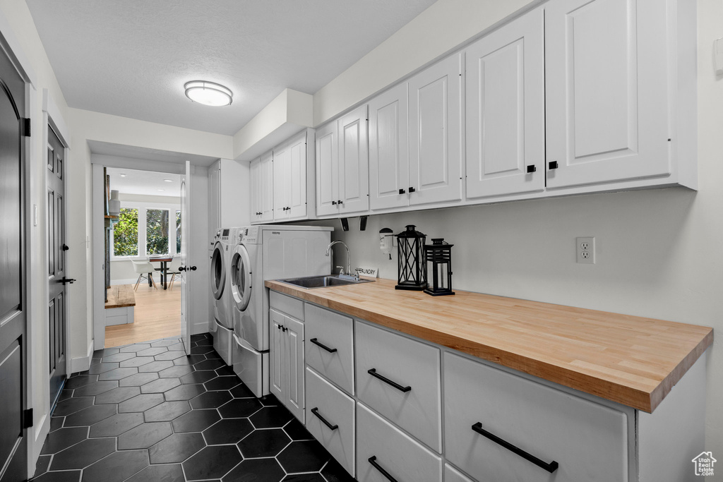 Laundry area featuring washing machine and clothes dryer, cabinet space, and dark tile patterned flooring