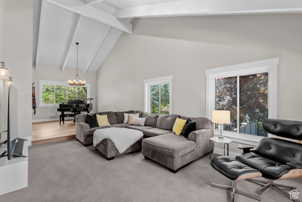 Living area featuring a chandelier, beam ceiling, plenty of natural light, high vaulted ceiling, and wood finished floors