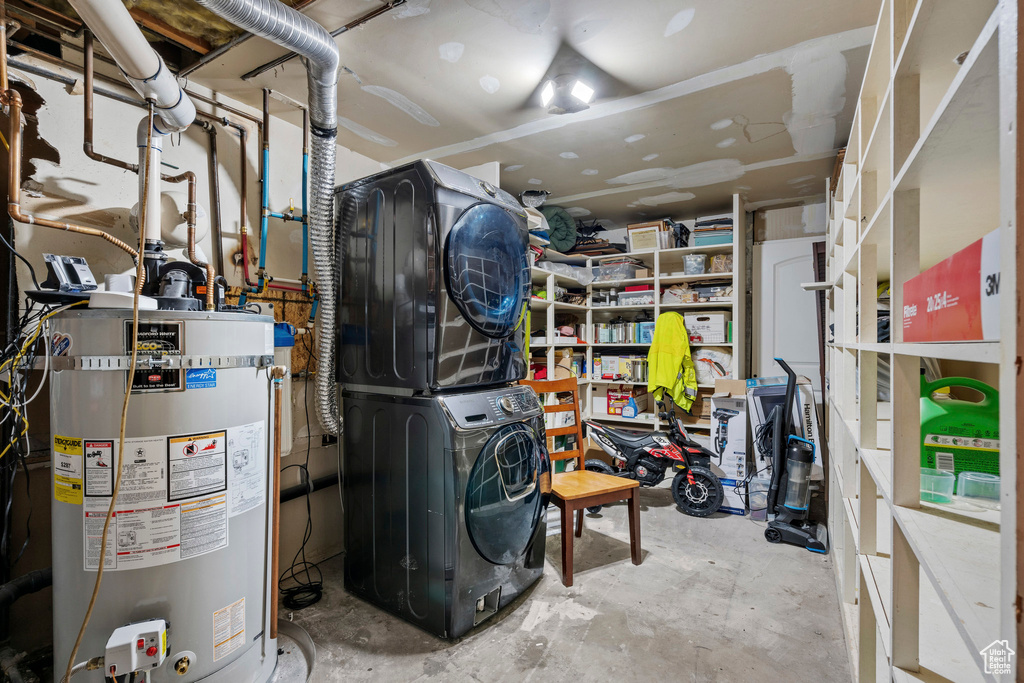 Utilities featuring stacked washer and clothes dryer and strapped water heater