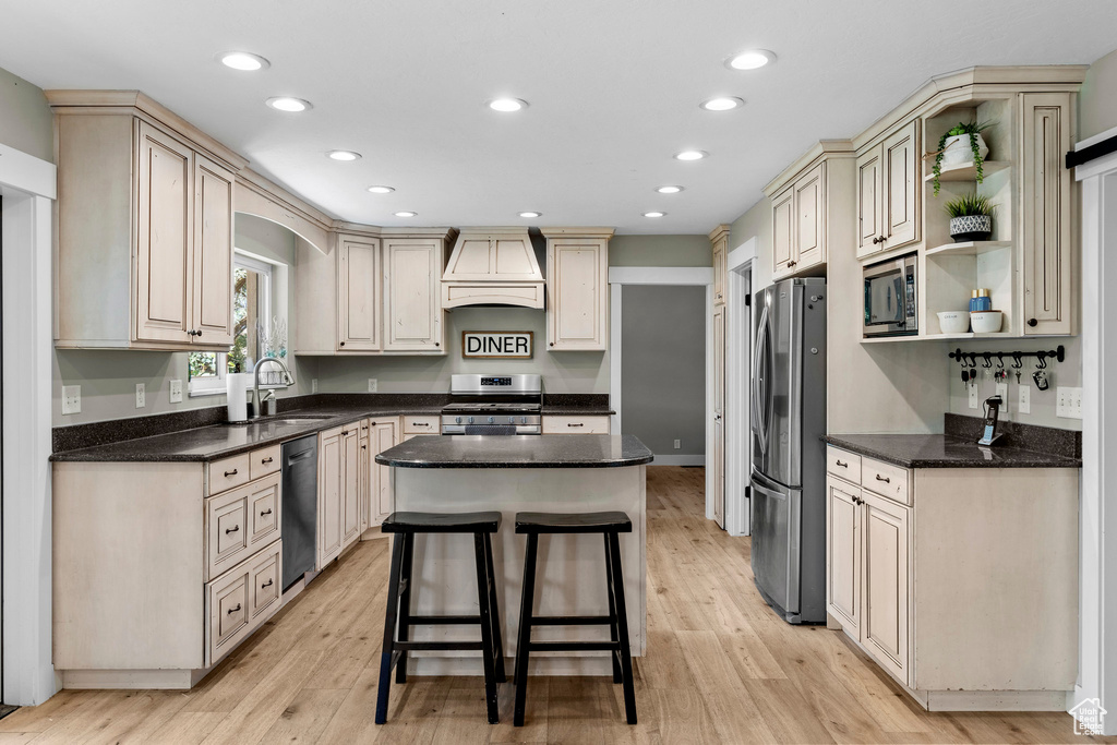 Kitchen with stainless steel appliances, premium range hood, a center island, recessed lighting, and open shelves