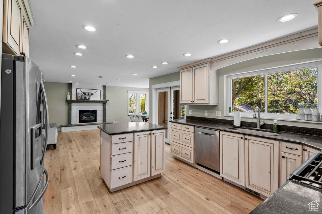 Kitchen featuring appliances with stainless steel finishes, open floor plan, a brick fireplace, recessed lighting, and light wood finished floors