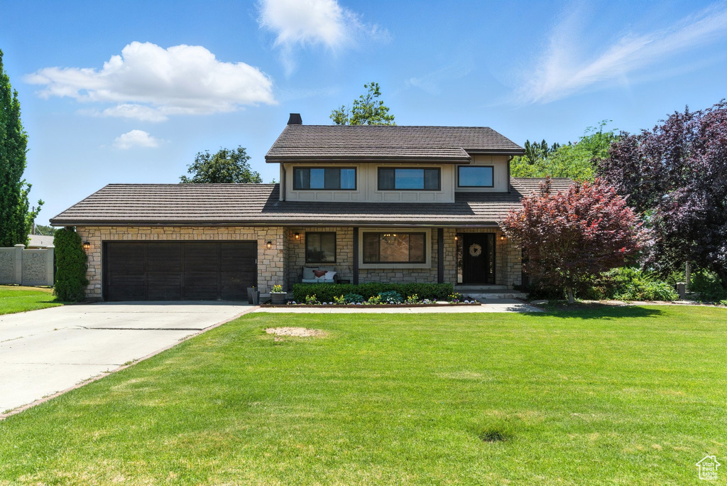 View of front facade with a garage, concrete driveway, stone siding, and a porch
