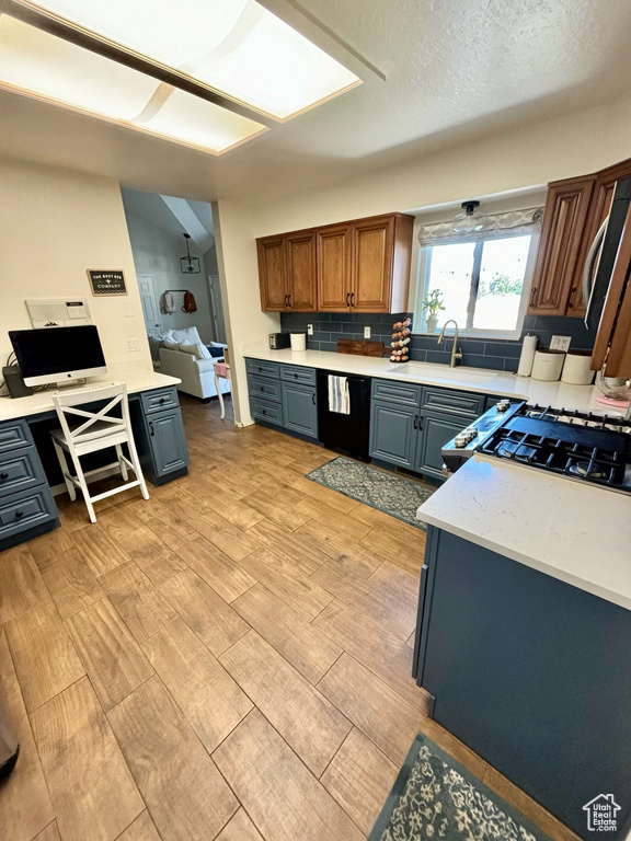 Kitchen with dishwasher, light wood-type flooring, light countertops, and a textured ceiling