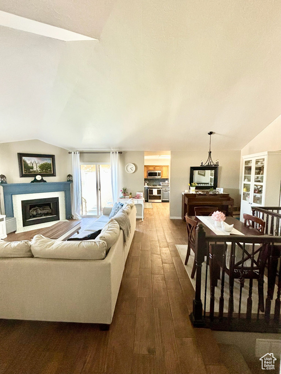 Living room with lofted ceiling, dark wood finished floors, and a glass covered fireplace