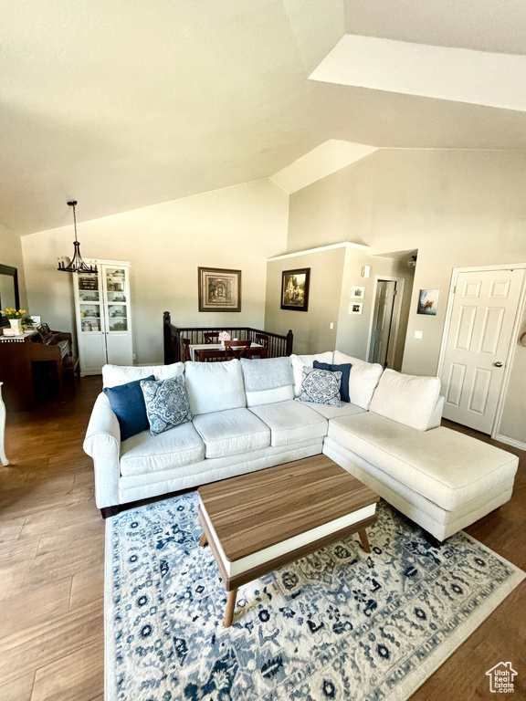 Living room featuring lofted ceiling, wood finished floors, and a chandelier