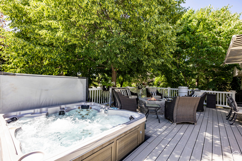 Wooden deck featuring a covered hot tub and an outdoor fire pit