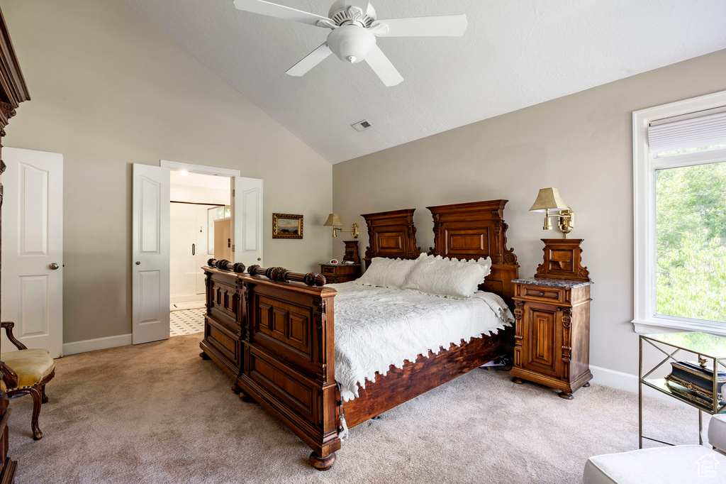 Bedroom with high vaulted ceiling, light colored carpet, connected bathroom, and a ceiling fan