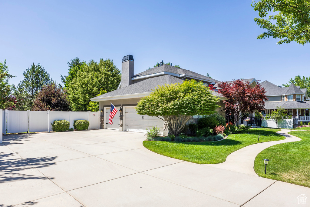 View of side of home with concrete driveway, a garage, and a chimney