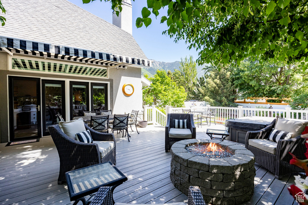 Wooden deck featuring a fire pit, outdoor dining area, and a mountain view