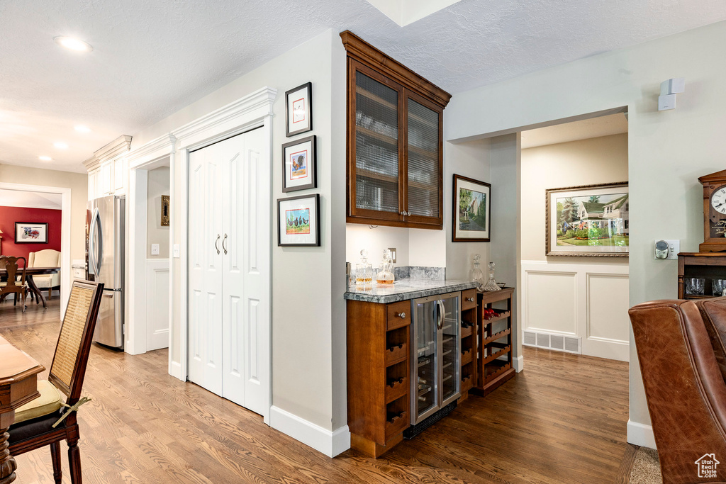 Indoor dry bar featuring freestanding refrigerator, wine cooler, wood finished floors, recessed lighting, and wainscoting