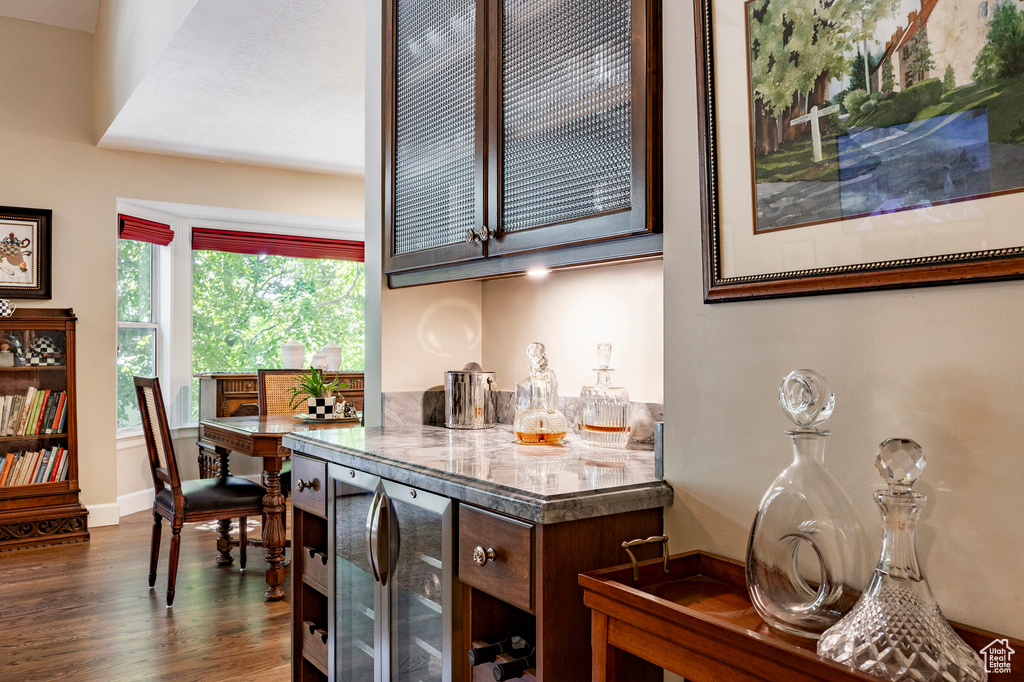 Indoor dry bar featuring beverage cooler and dark wood-type flooring
