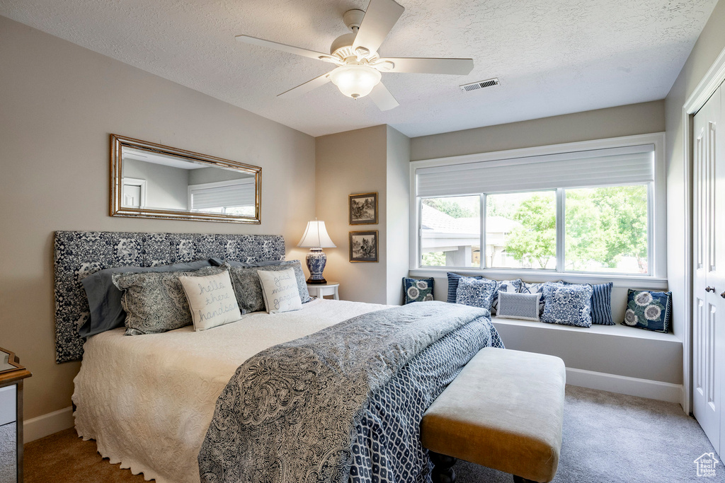 Carpeted bedroom featuring a textured ceiling and a ceiling fan