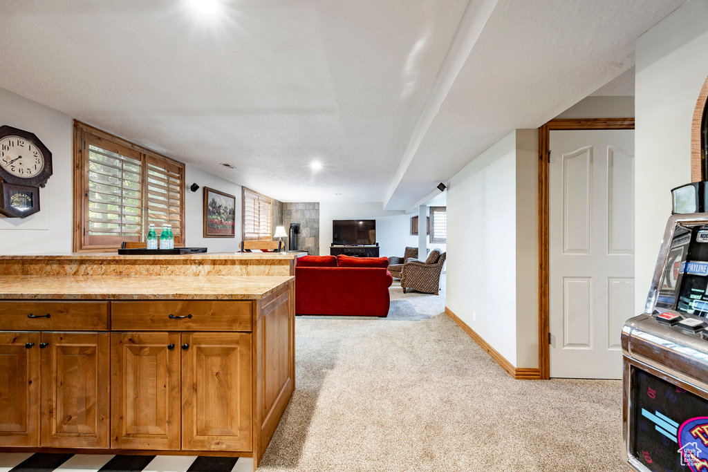 Kitchen with light colored carpet and brown cabinetry
