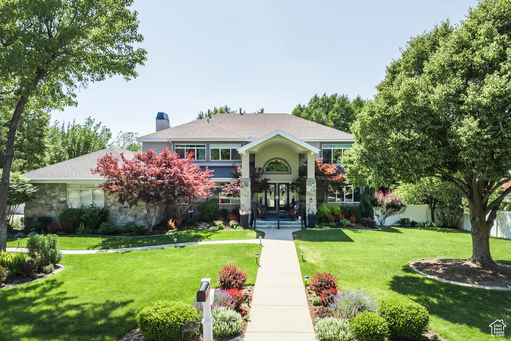 View of front of house featuring stone siding, a chimney, and a shingled roof