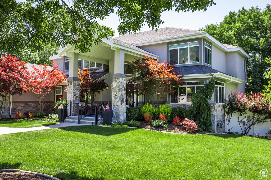 View of front of house with stone siding, stucco siding, and a front lawn
