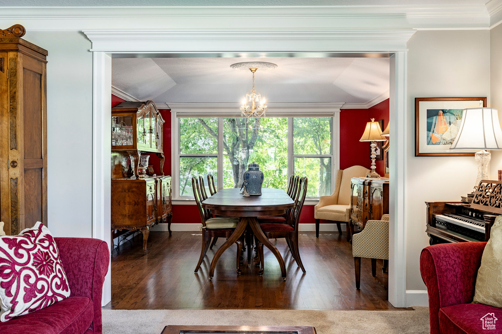 Dining space with a chandelier, wood finished floors, and ornamental molding