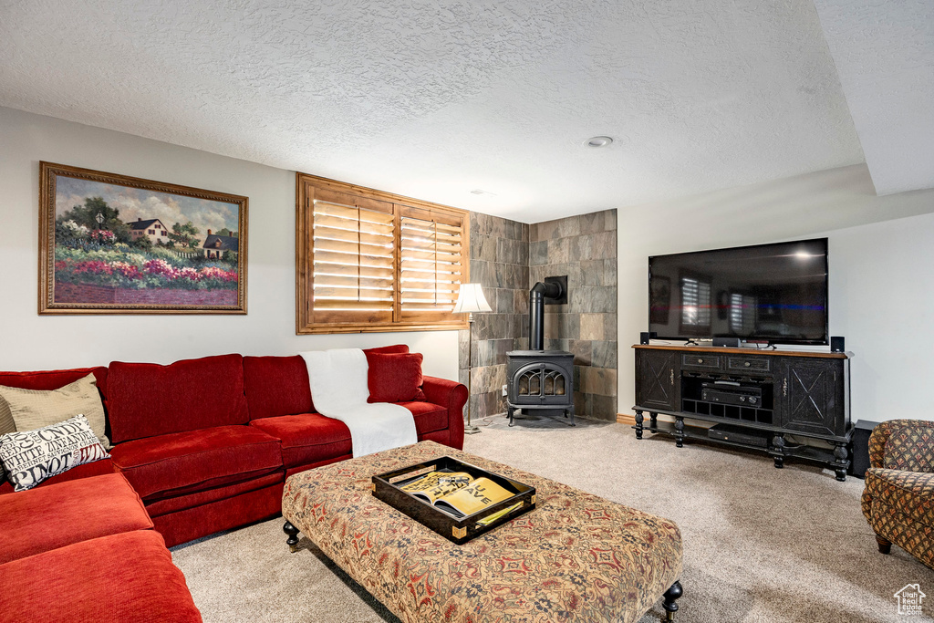 Carpeted living area with a wood stove and a textured ceiling