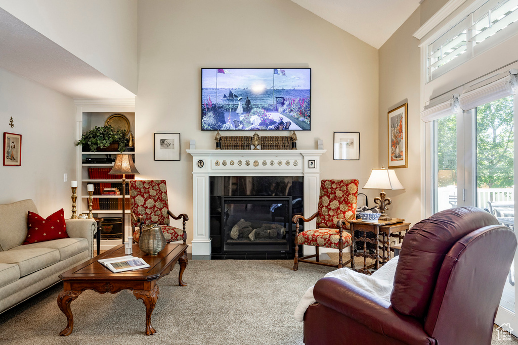 Carpeted living area with a glass covered fireplace and high vaulted ceiling