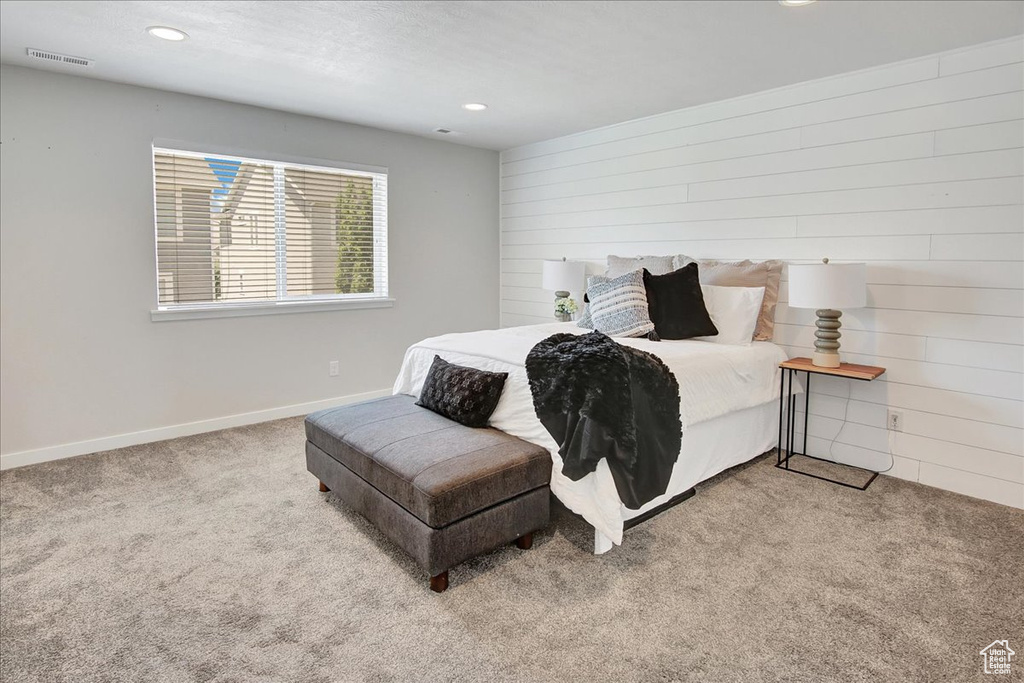 Carpeted bedroom featuring wood walls and recessed lighting